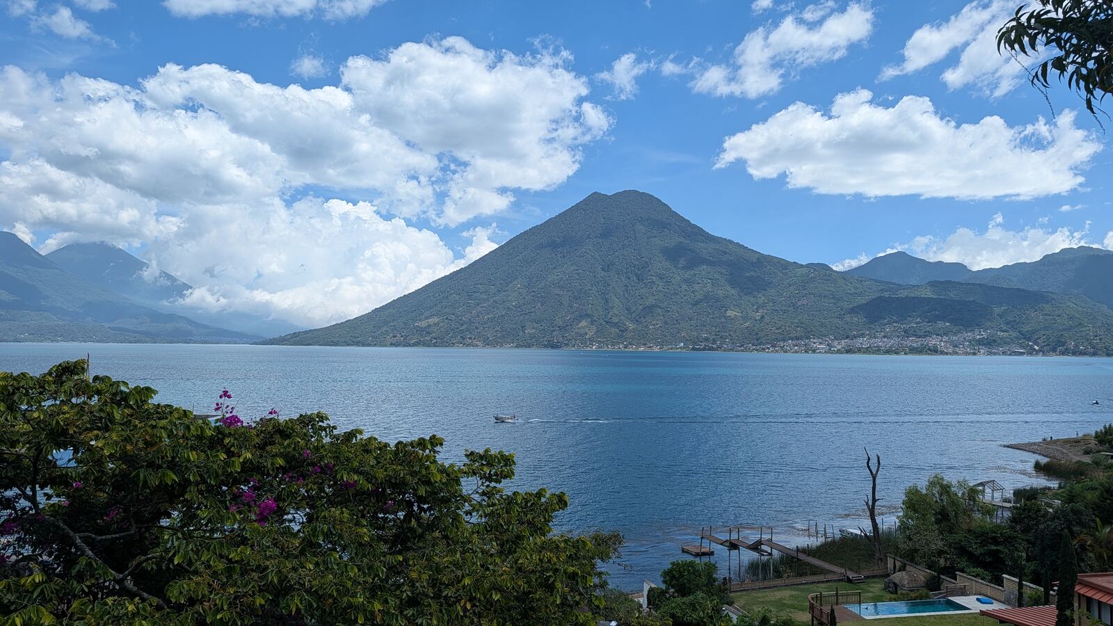 Clouds over the volcano and the lake, seen past flowering trees