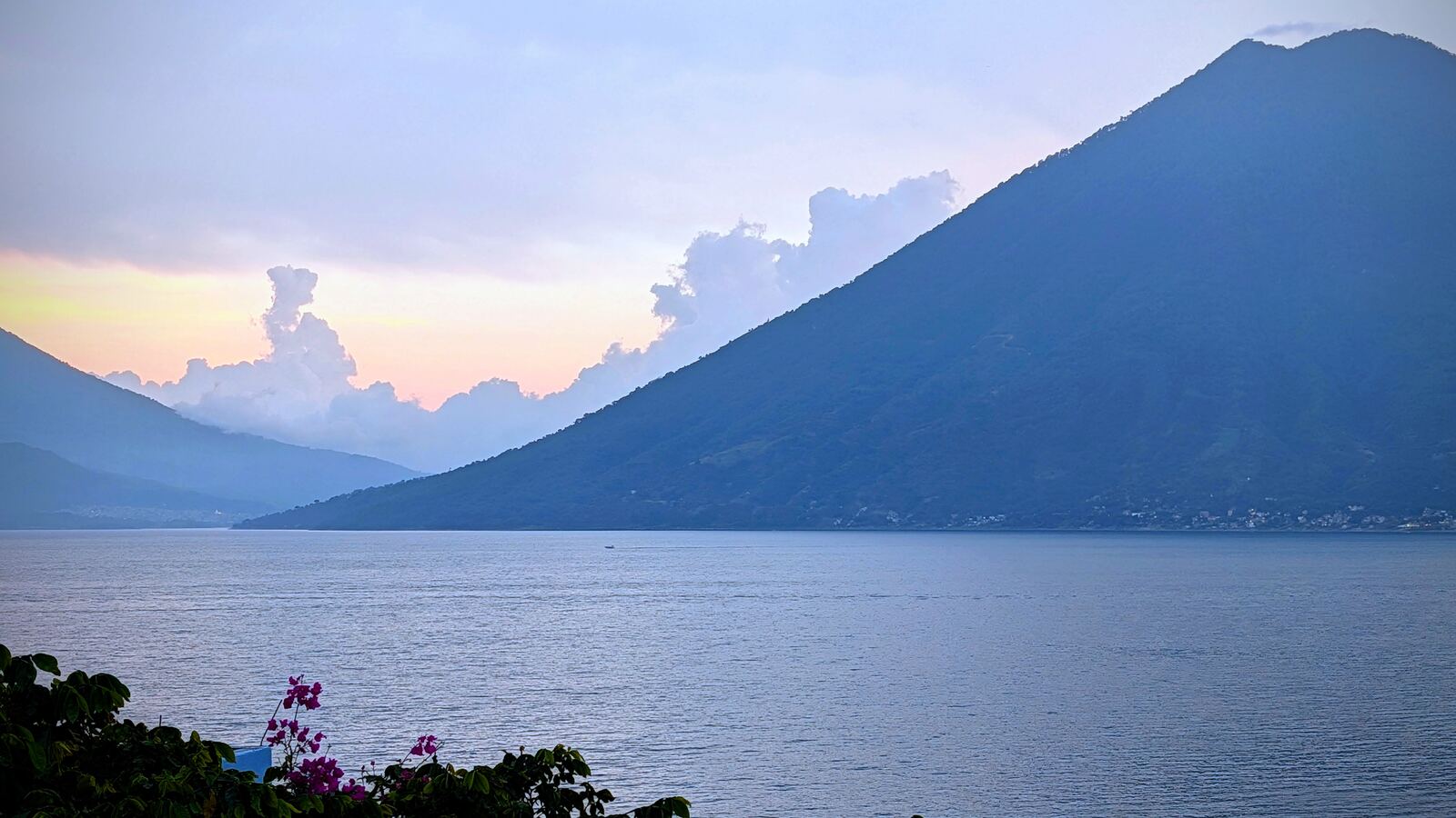 Lake Atitlán at dusk, a volcano dark against a pink sky
